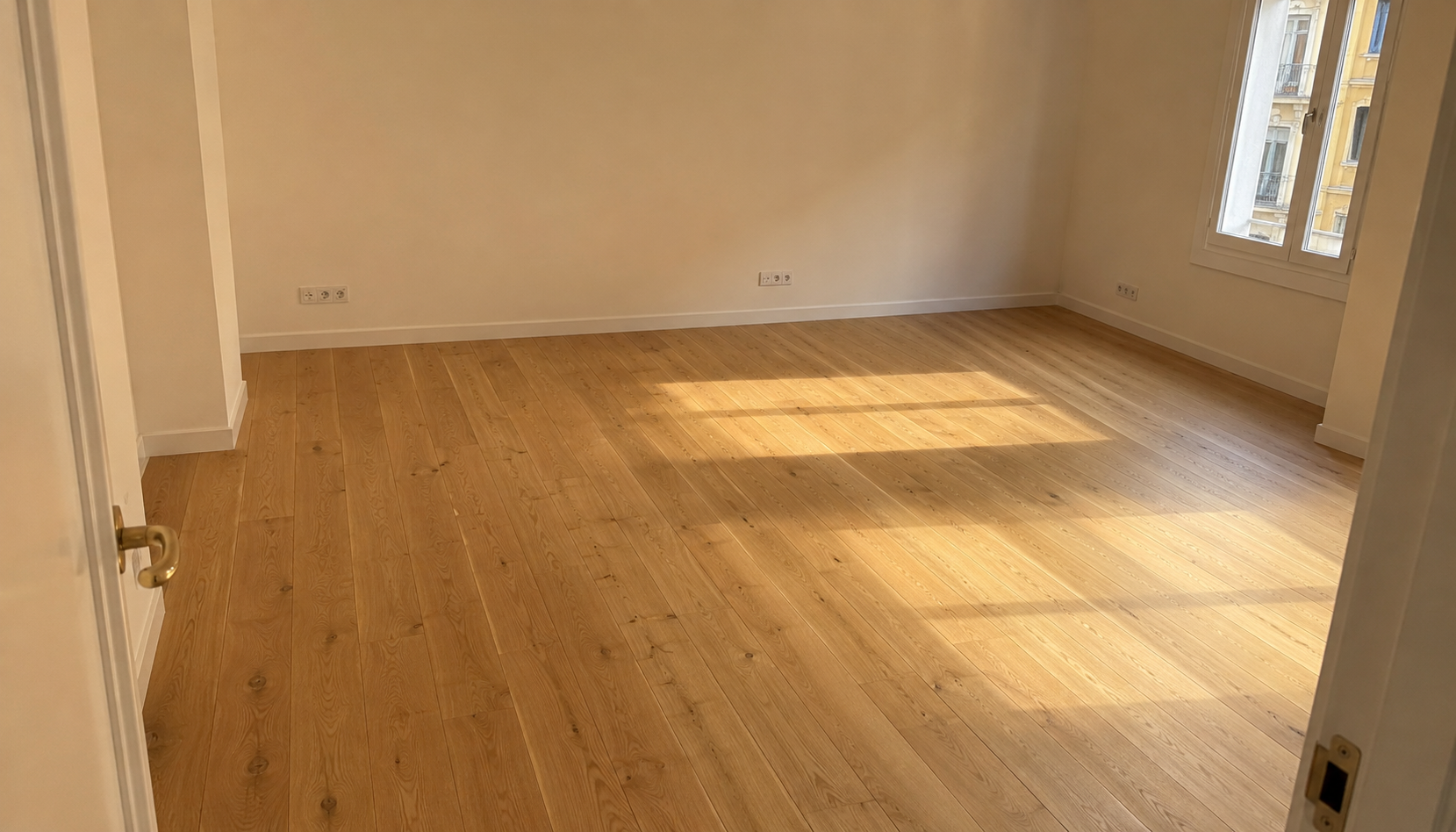 Salón principal reformado con suelo de roble, paredes en tono cálido y luz natural
