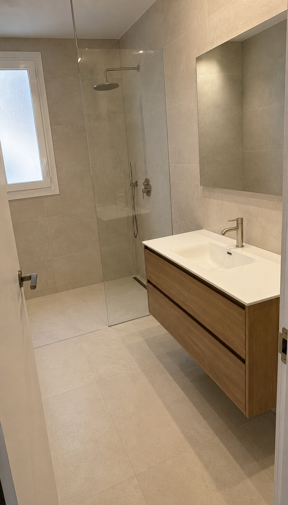 Baño renovado con ducha de obra a ras y revestimiento en gran formato crema