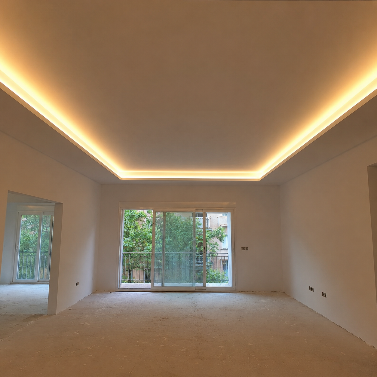 Salón con falso techo de pladur perimetral e iluminación LED indirecta cálida