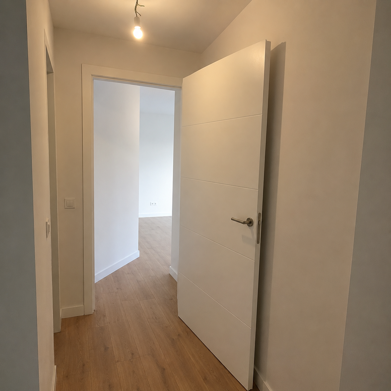Recibidor de vivienda renovado con puerta interior nueva y suelo de madera